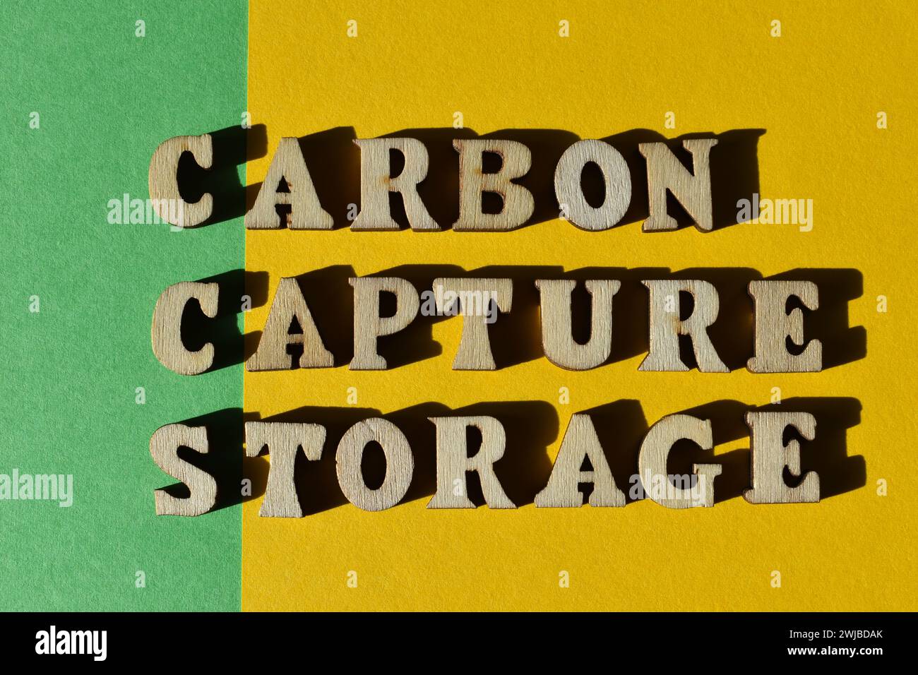 CCS, abbreviation for Carbon Capture Storage and words in wooden alphabet letters isolated on green and yellow background as banner headline Stock Photo