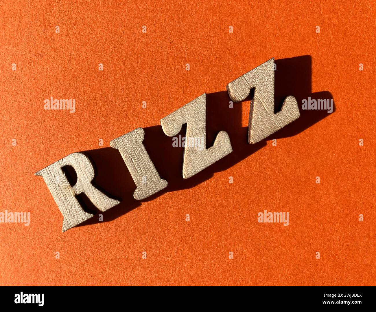 Rizz, slang word for charisma used by Gen Z, in wooded alphabet letters isolated on bright orange background Stock Photo