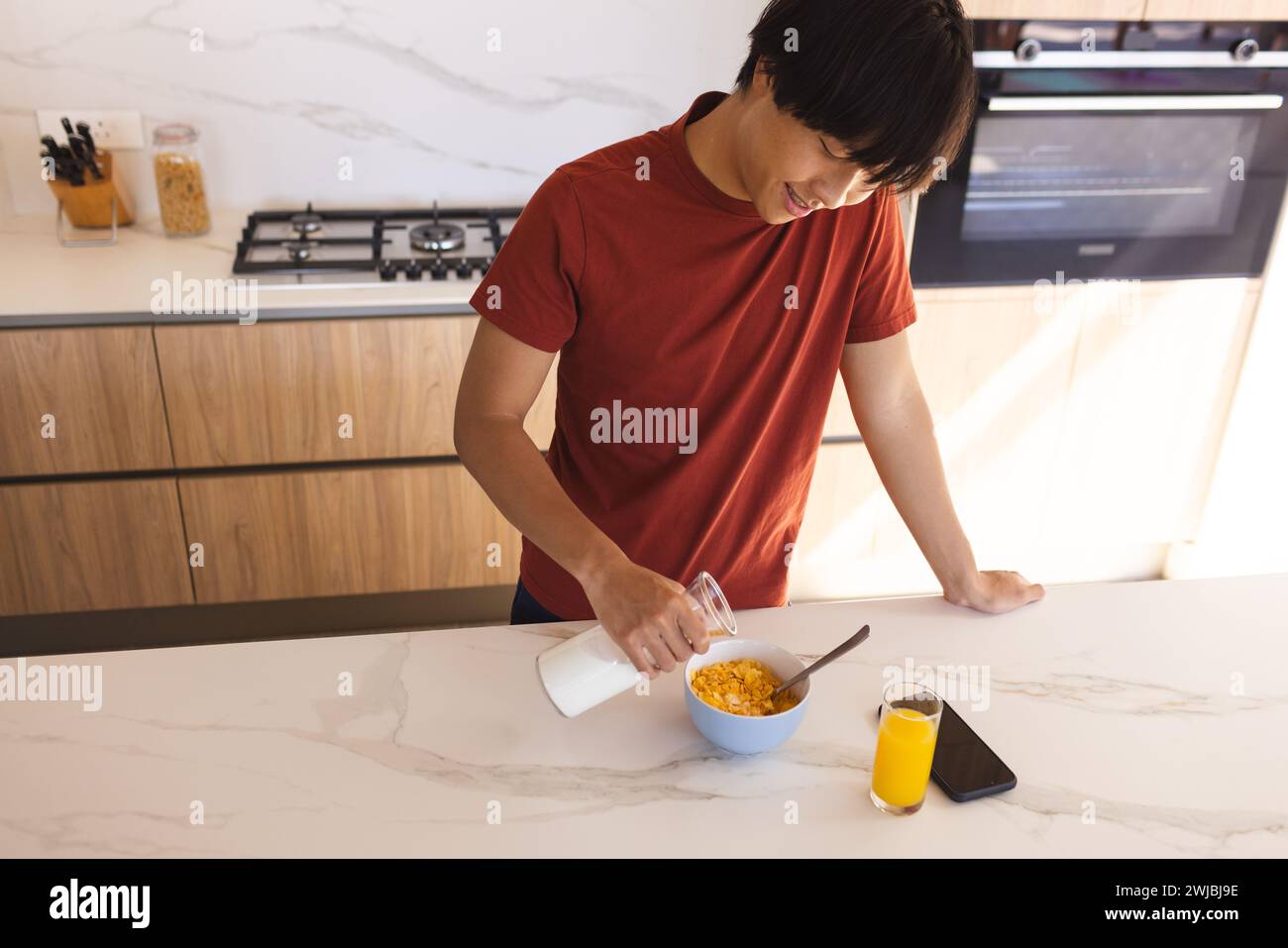 Teenage Asian boy prepares breakfast in a modern home kitchen Stock Photo