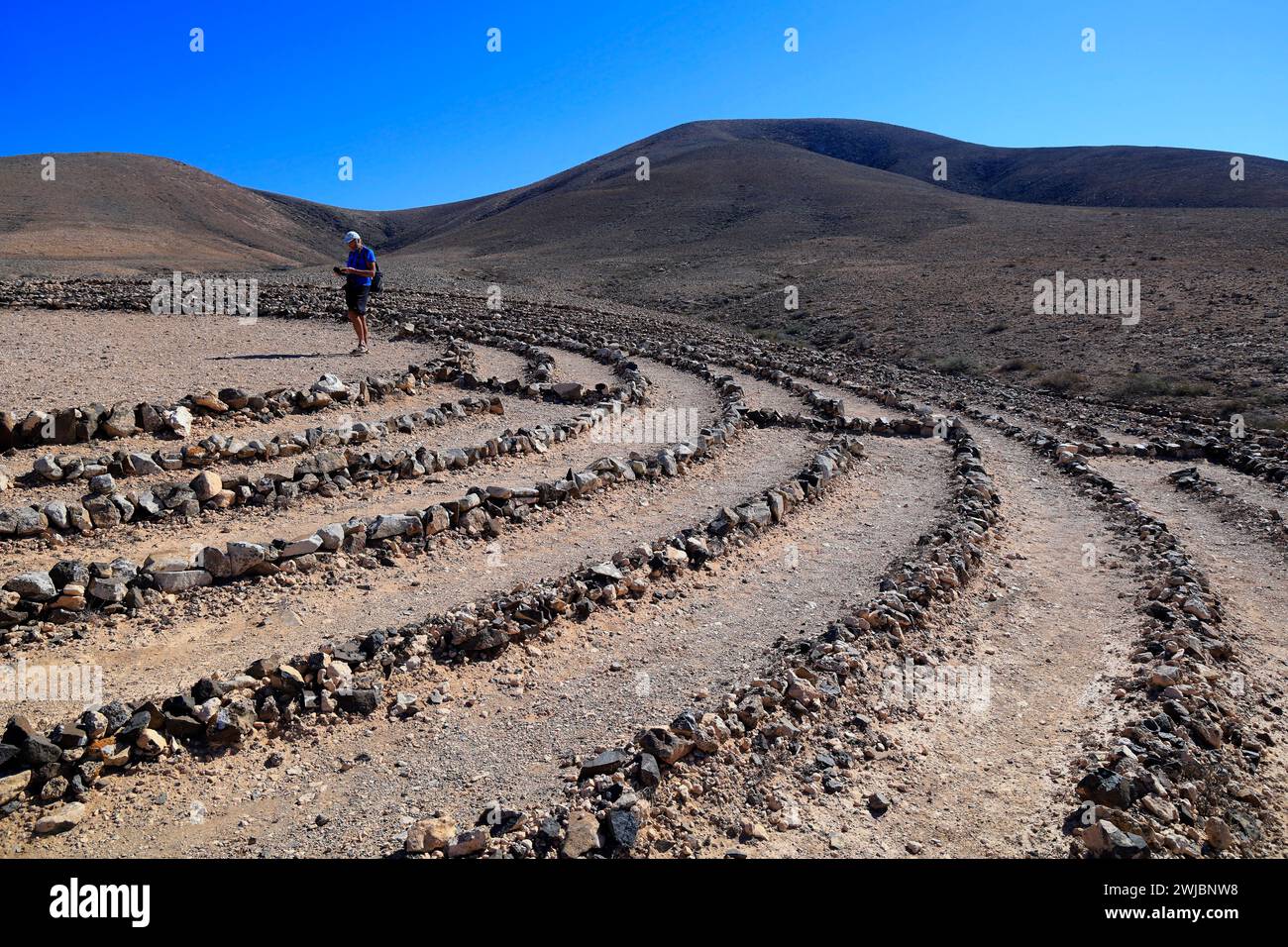 Man visiting Wolf Patton's Labyrinth - low stone maze in the middle of nowhere near El Cotillo, Fuerteventura. Taken November 2023 Stock Photo
