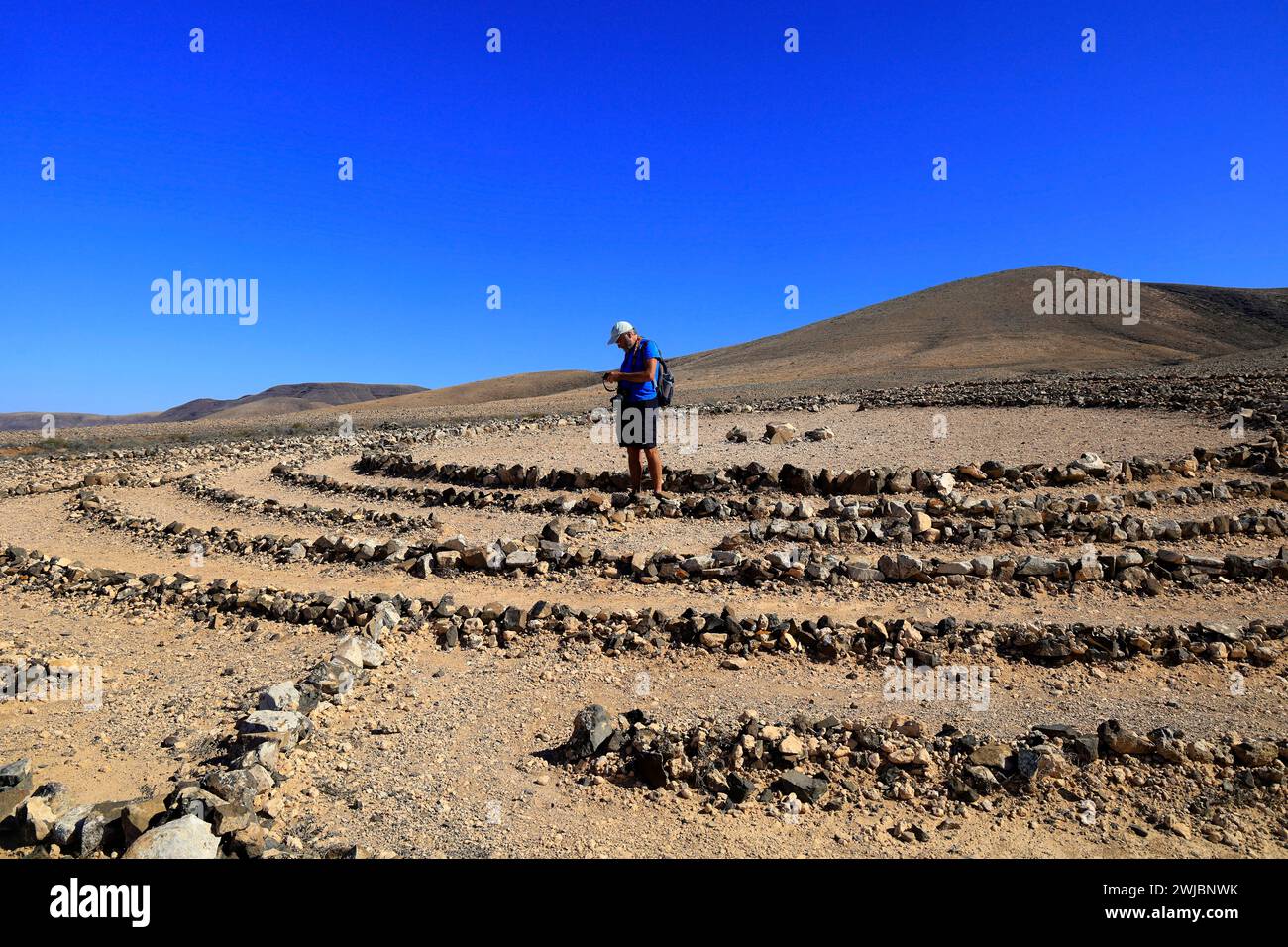 Man visiting Wolf Patton's Labyrinth - low stone maze in the middle of nowhere near El Cotillo, Fuerteventura. Taken November 2023 Stock Photo