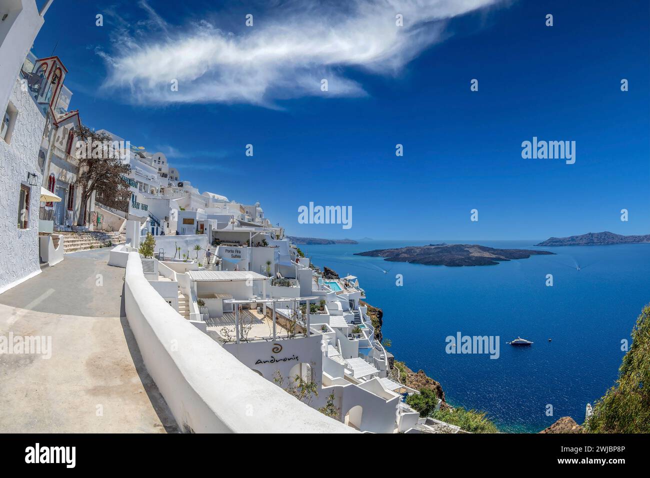FIRA, SANTORINI ISLAND, GREECE - JUNE 21, 2021: Typical white architecture of Fira (Thira) city. Volcanic island Nea Kameni in background. Stock Photo