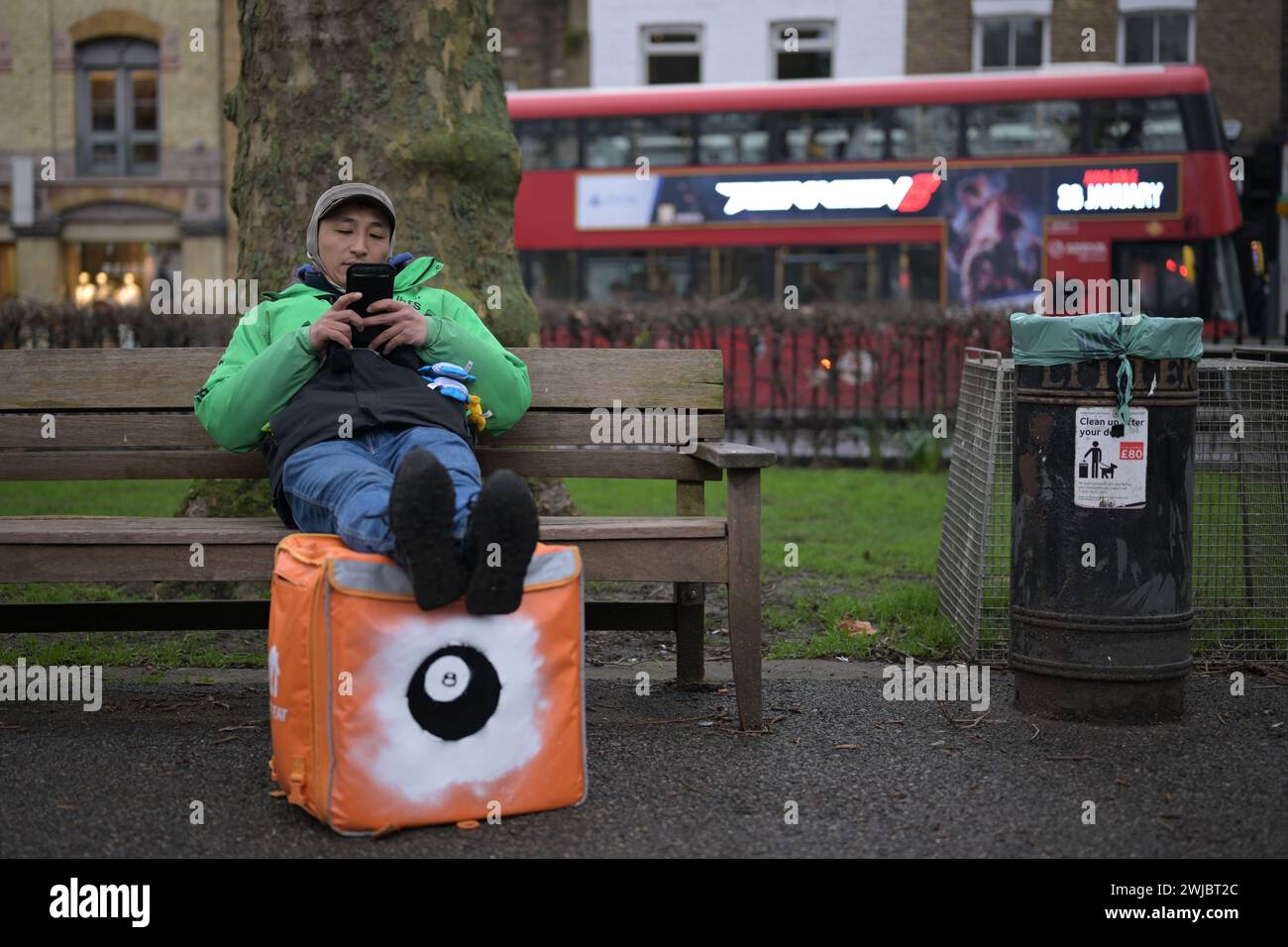 14th February 2024: An Uber Eats food courier takes a break between jobs in Islington Green, London. Deliveroo and Uber Eats couriers are striking tonight between five and ten o’clock to secure better working conditions and pay. Stock Photo