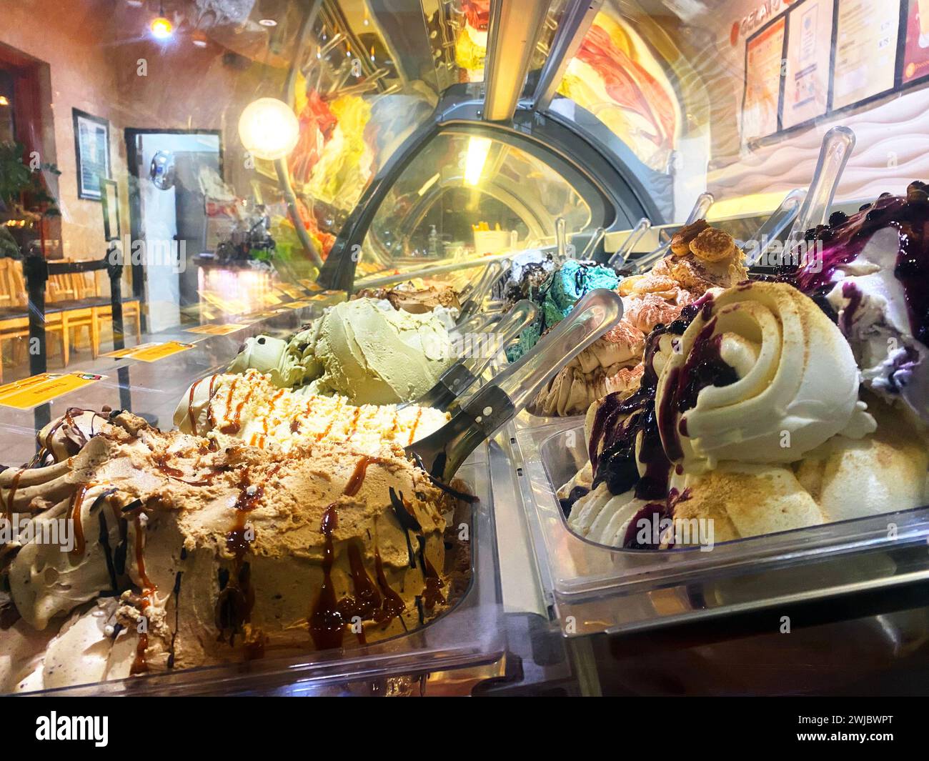 Tubs of gelato at a gelateria waiting to be scooped for customers, interior view of an ice cream cooler or freezer with colourful artisanal flavors Stock Photo