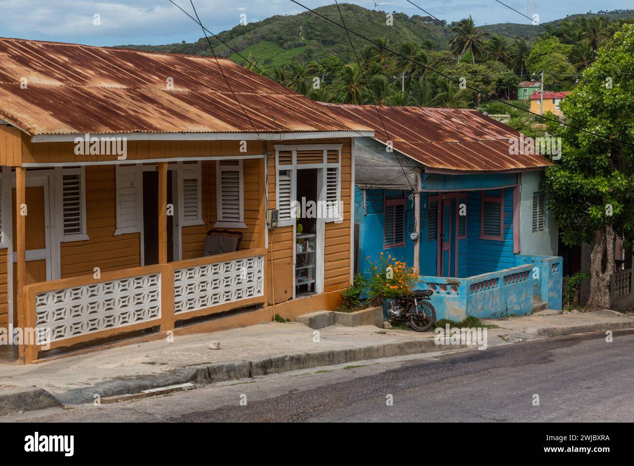 Two colorful houses with rusty corrugated metal roofs in the Barahona Province in rural Dominican Republic. Stock Photo