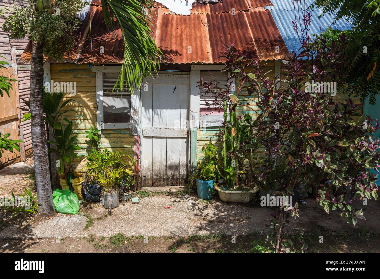 A small, traditional wooden slab house with a rusty corrugated metal roof in the rural Dominican Republic. Stock Photo