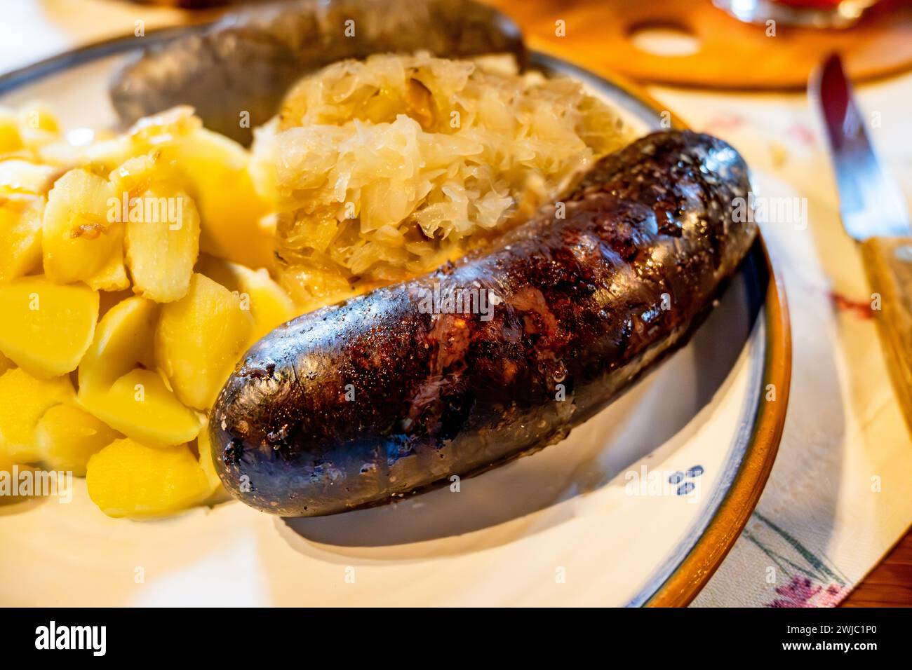 Grilled black pudding (sausage) with stewed cabbage and boiled potato, closeup. Stock Photo