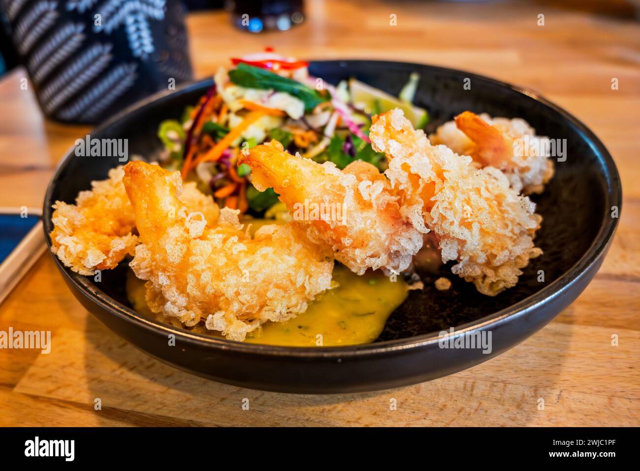 Fried tempura shrimp with mango sauce and salad in bowl on table, closeup. Stock Photo
