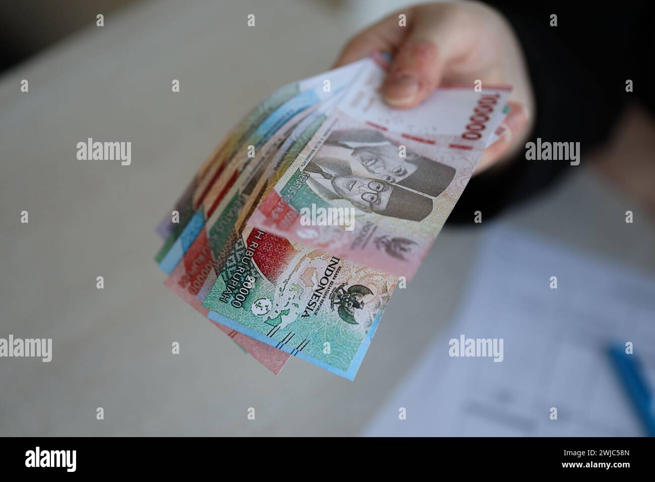 Female accountant hand give bunch of many indonesian rupiah money bills of new series close up Stock Photo