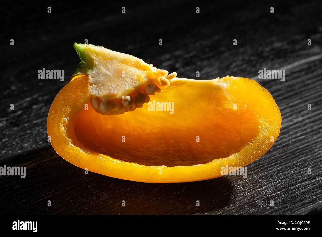 sliced yellow bell pepper on black wood background Stock Photo