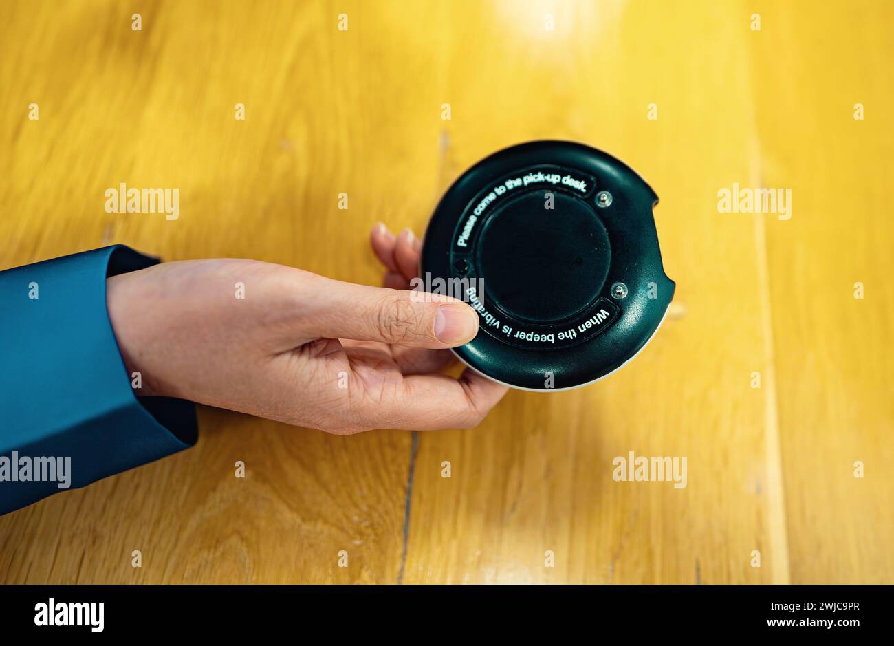 Woman holds a restaurant pager. Queue calling system. Stock Photo