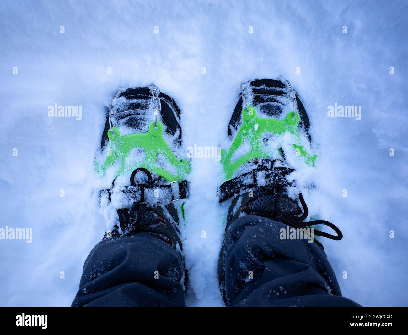 A top-down close-up view of mountaineering crampons on fresh snow Stock Photo