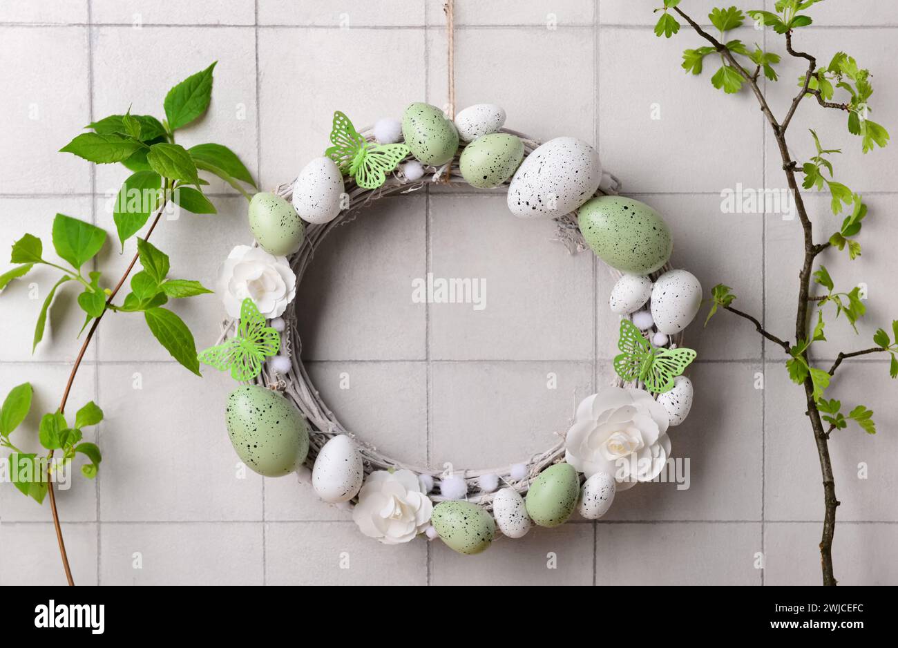 Easter wreath made of flowers, eggs and butterflies with branches ...