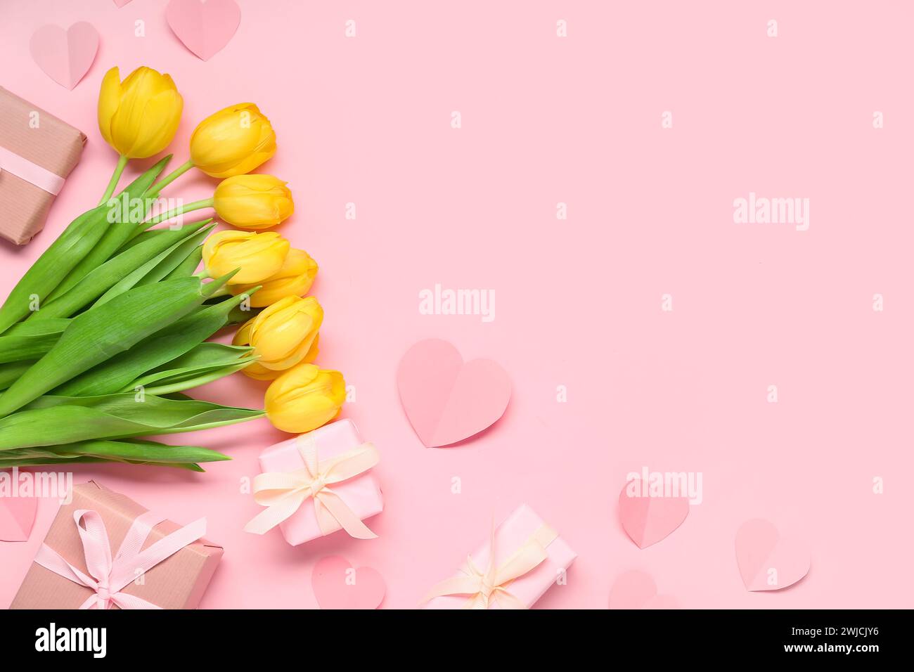 Yellow tulips, paper hearts and gift boxes on pink background Stock ...
