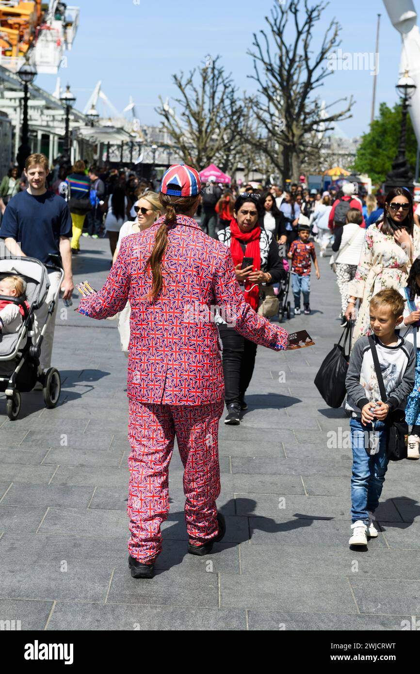 Man in Union Jack suit handing out leaflets to tourists by the London Eye, Southbank, London, UK.  26 May 2023 Stock Photo