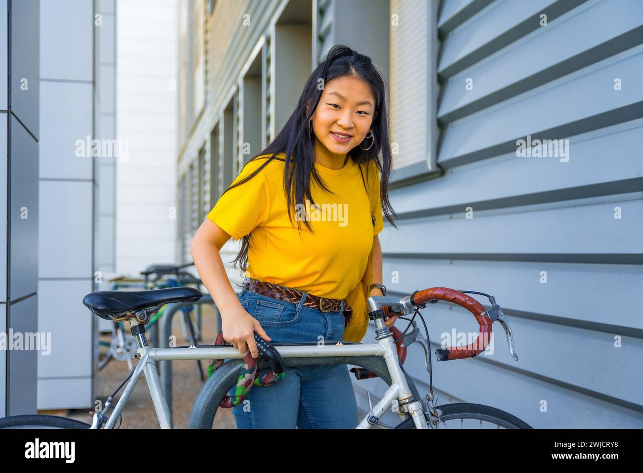 Portrait of a young chinese cute woman parking a bike in the street Stock Photo