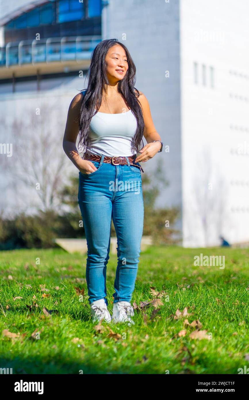 Vertical photo of a chinese cool student standing on the grass of the campus Stock Photo