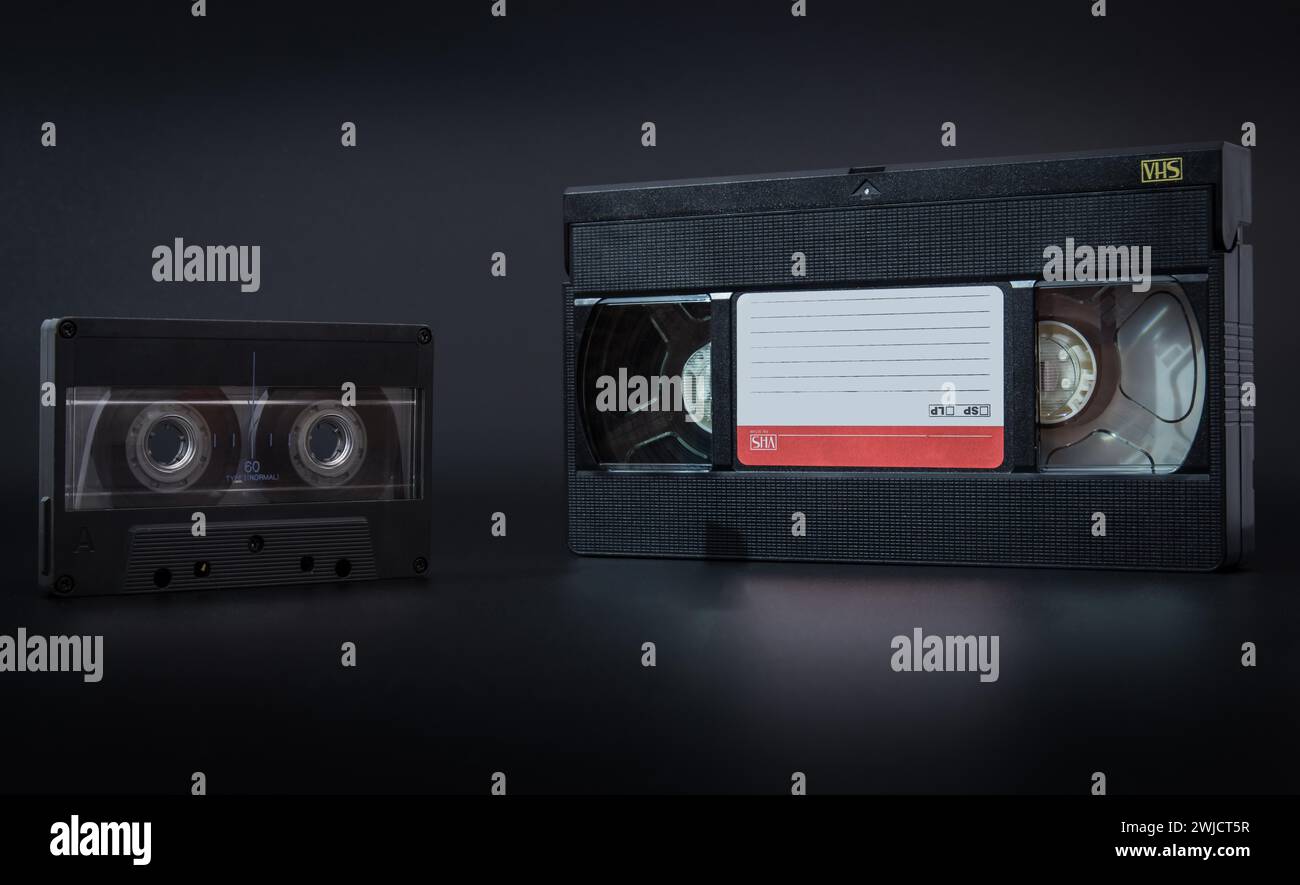 A vintage cassette tape and VHS tape against a dark background Stock Photo