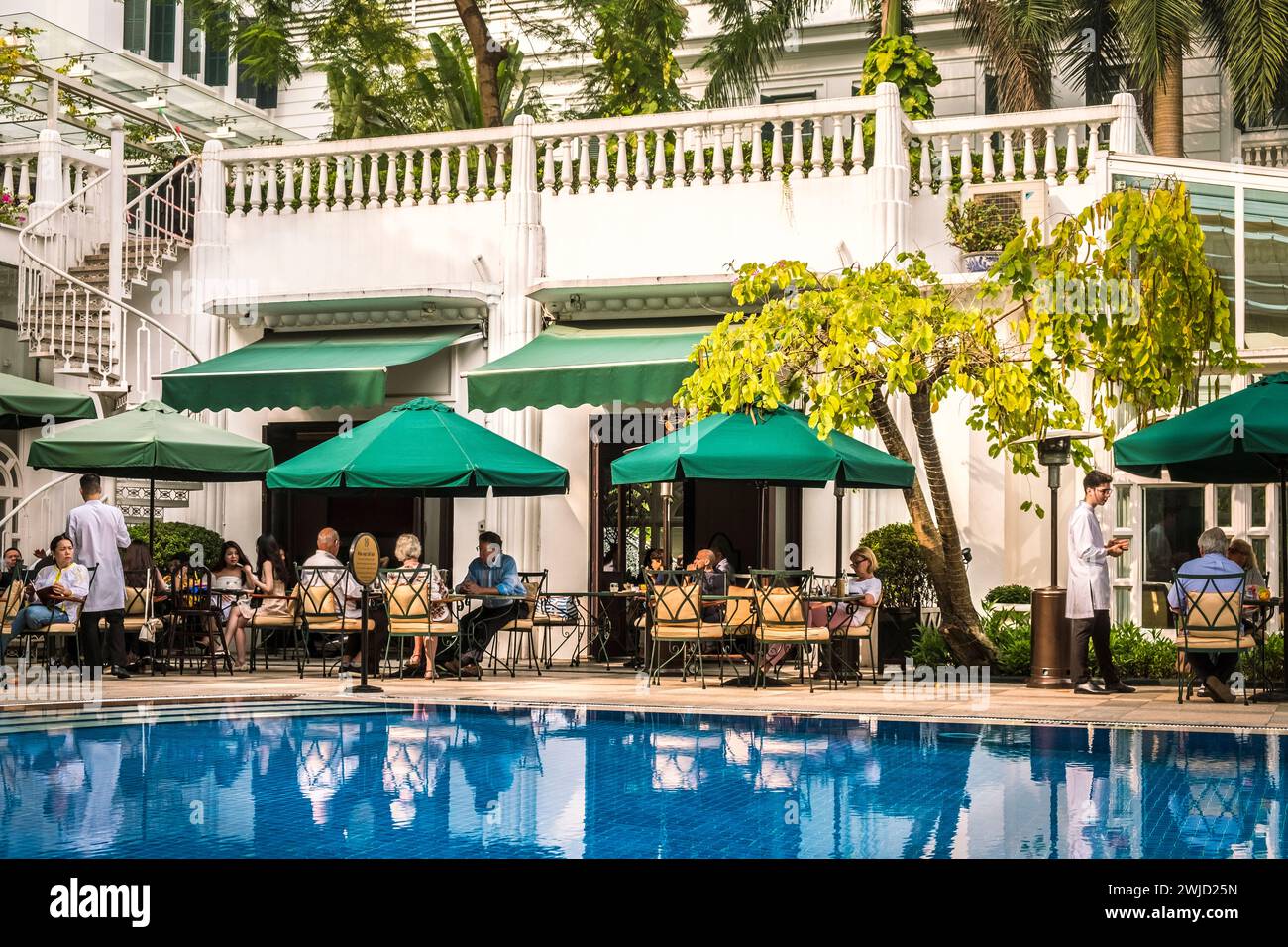 Hotel guests have lunch at the courtyard garden restaurant, Sofitel Legend Metropole, Hanoi Vietnam Stock Photo