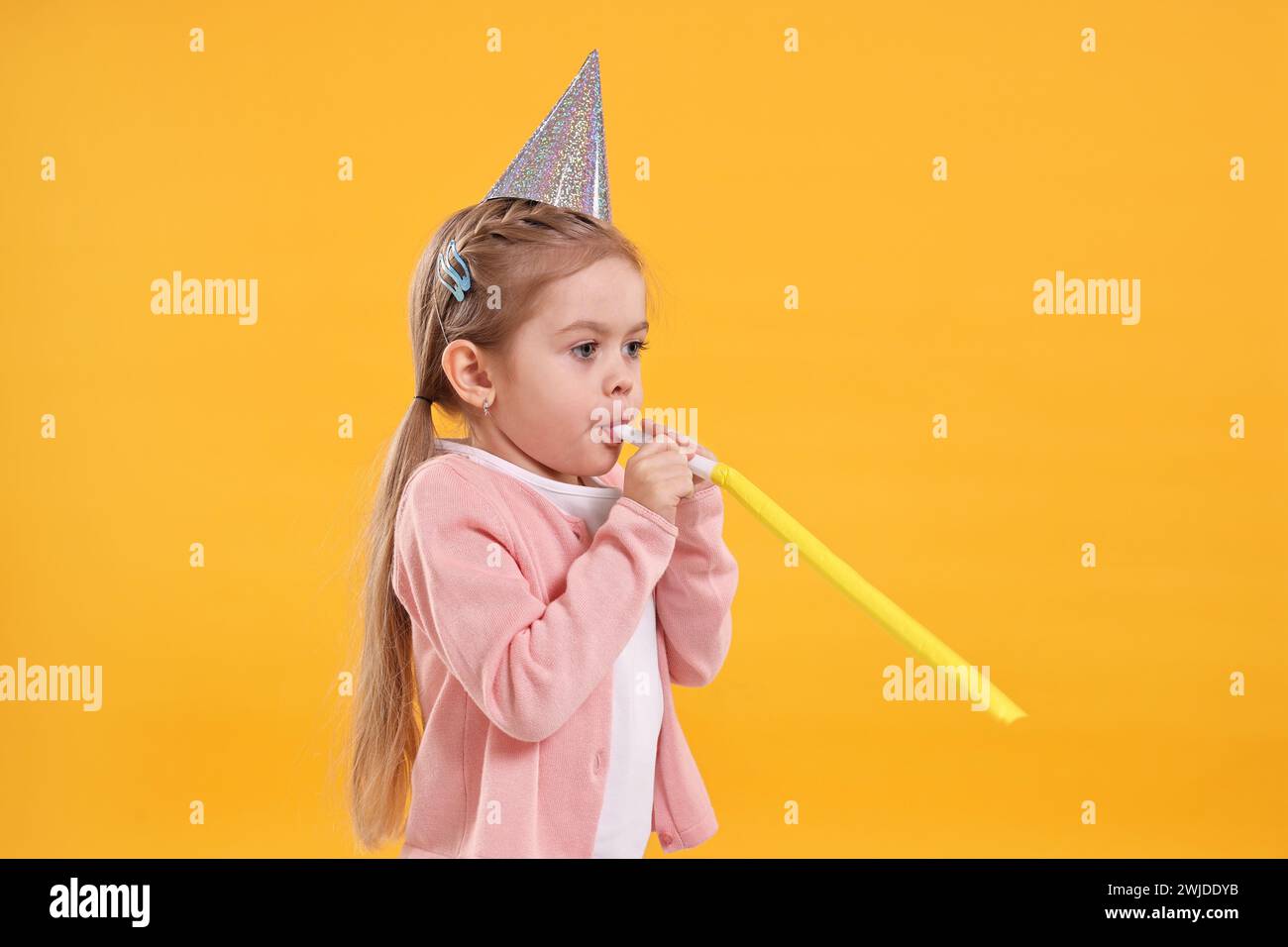 Birthday celebration. Cute little girl in party hat with blower on ...