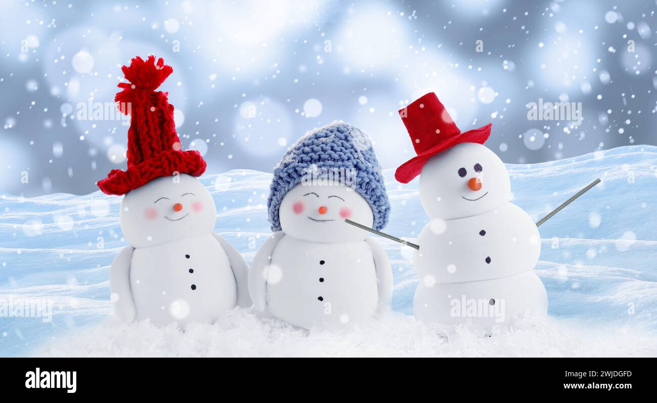 Cute decorative snowmen in hats outdoors on snowy day, banner design ...