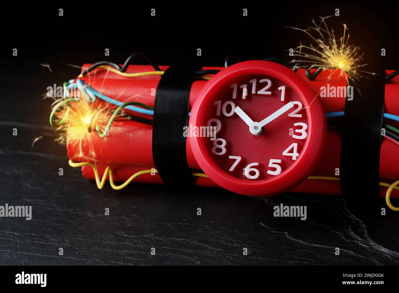 Dynamite time bomb with burning wires on black table, closeup Stock Photo