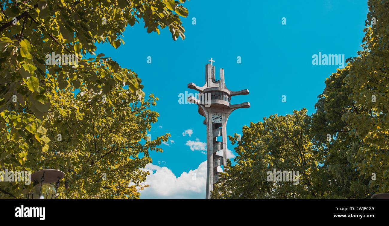 Observation tower with a clock in Banja Luka on a sunny day in spring. Beautiful skies and trees surrounding this magnificent tower in brutalist style Stock Photo