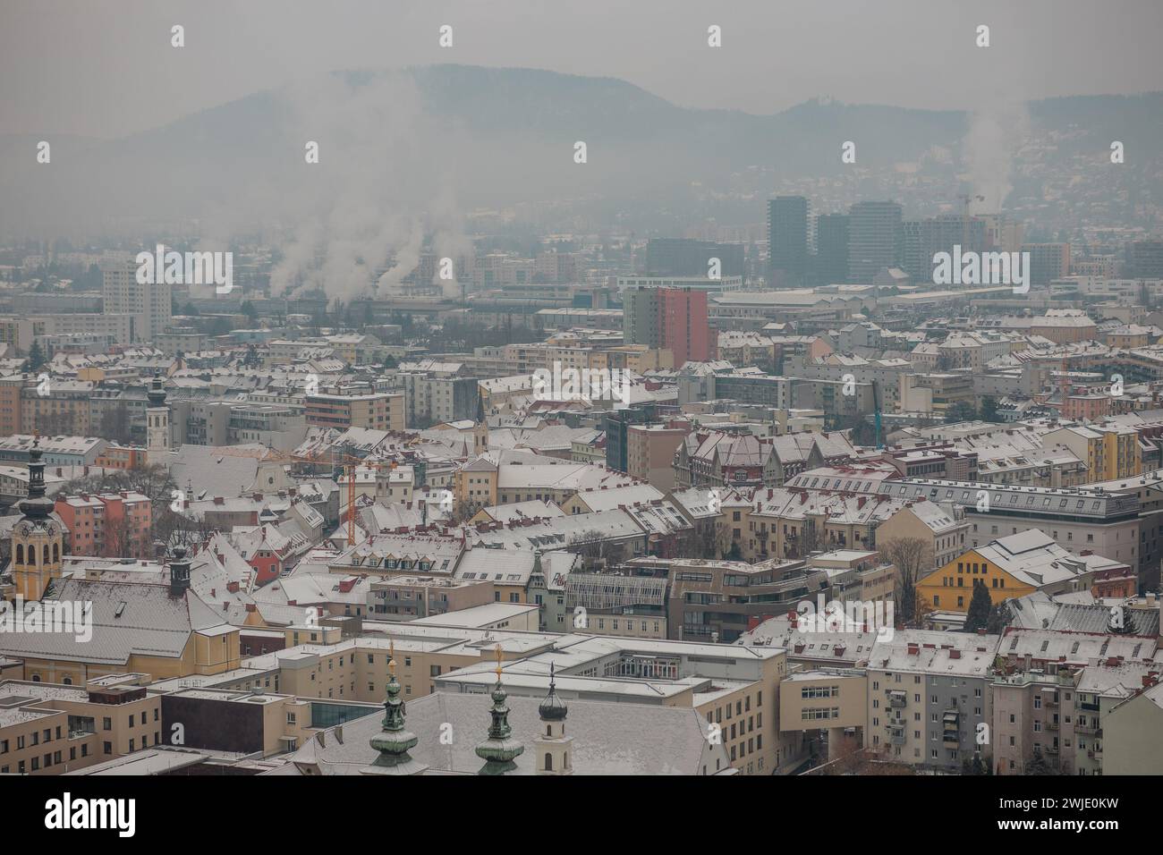 White winter panorama of city of Graz, Austria from famous schlossberg hill. Cold cloudy day, mist rising up. Stock Photo