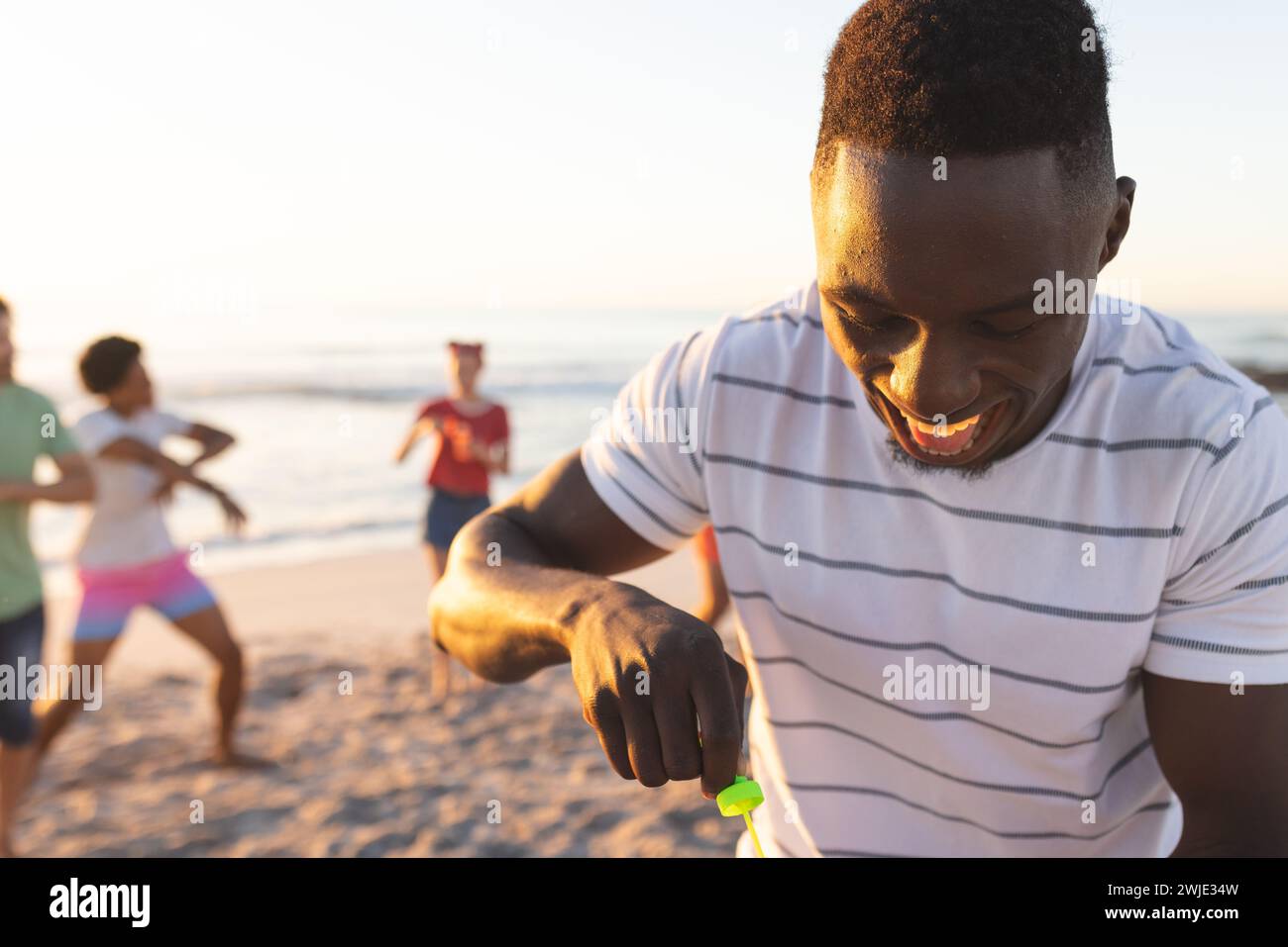 Young African American man prepares to blow bubbles on the beach Stock Photo