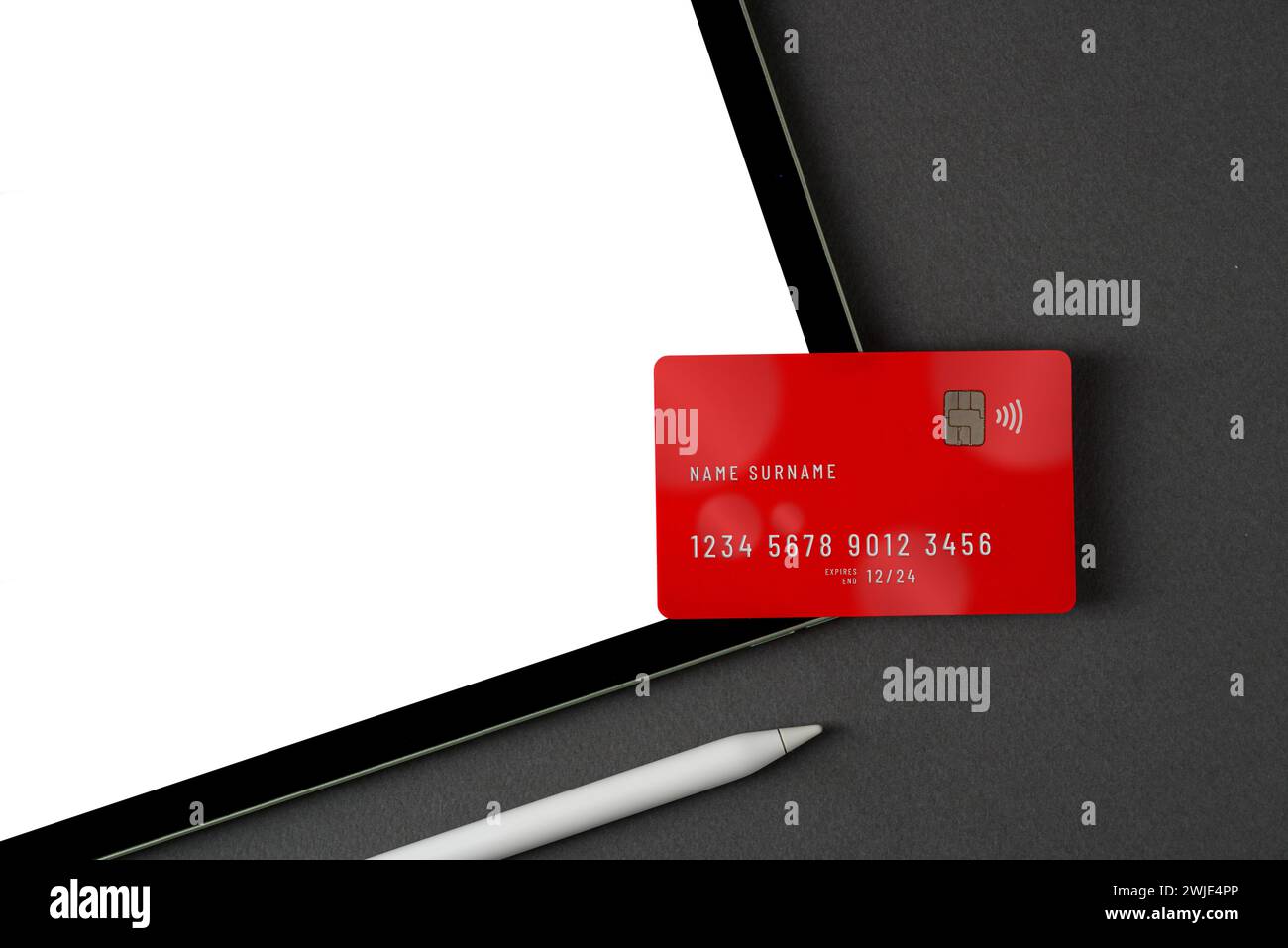 Credit card lying on tablet with blank screen on dark gray table Stock Photo