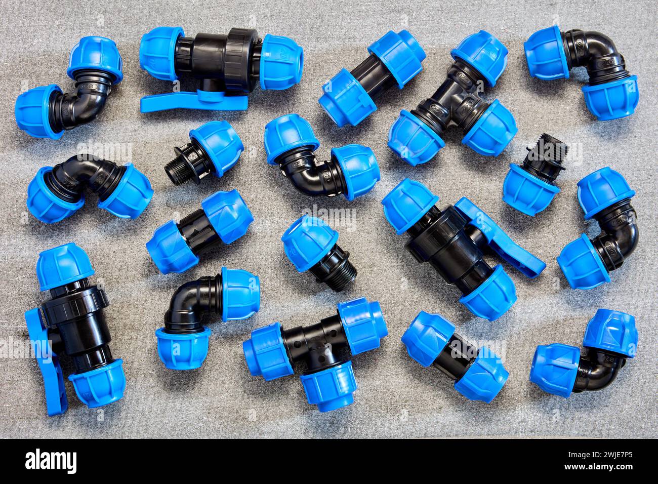 Polypropylene compression clamping fittings for pipeline system made of HDPE pipes laid out on gray slate sheet. Stock Photo