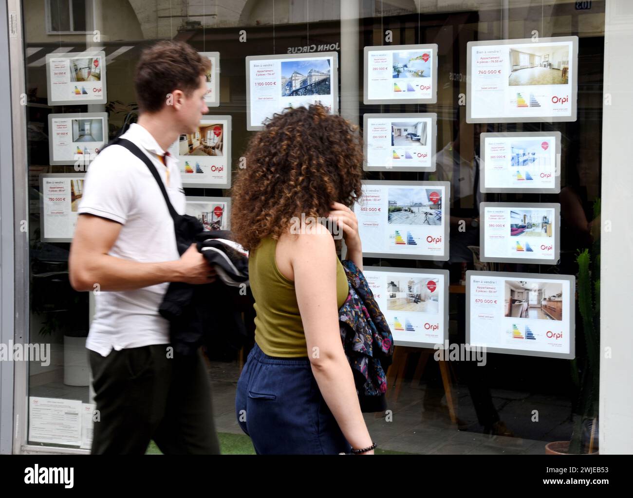 Estate agency in Paris (France). Couple looking at the classified advertisements through the window Stock Photo