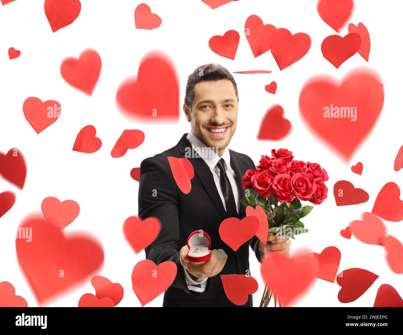 Handsome guy in a suit holding a bouquet of roses and a ring in a box ...