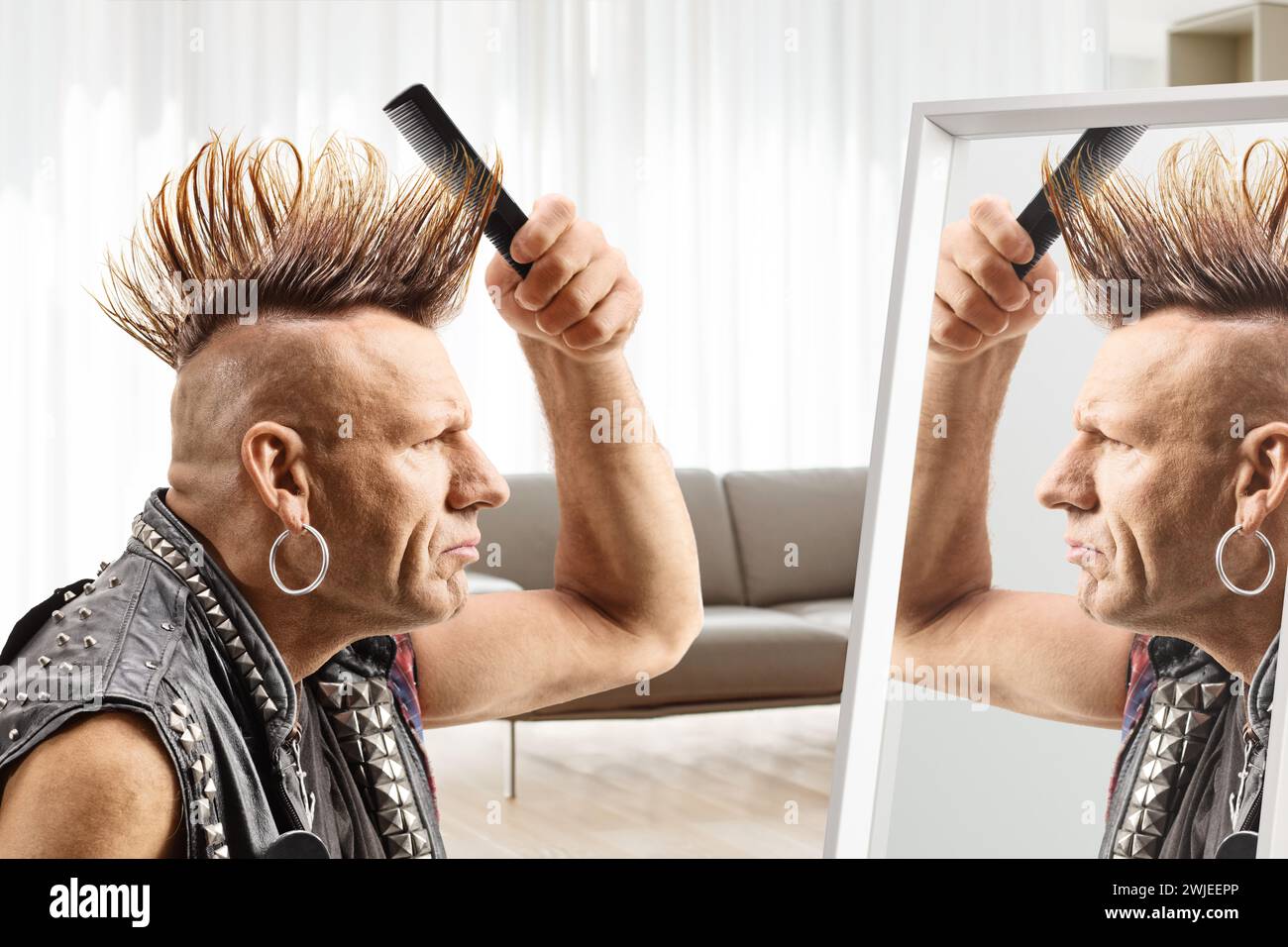 Man combing his mohawk hairstyle with a brush in front of a mirror at home Stock Photo