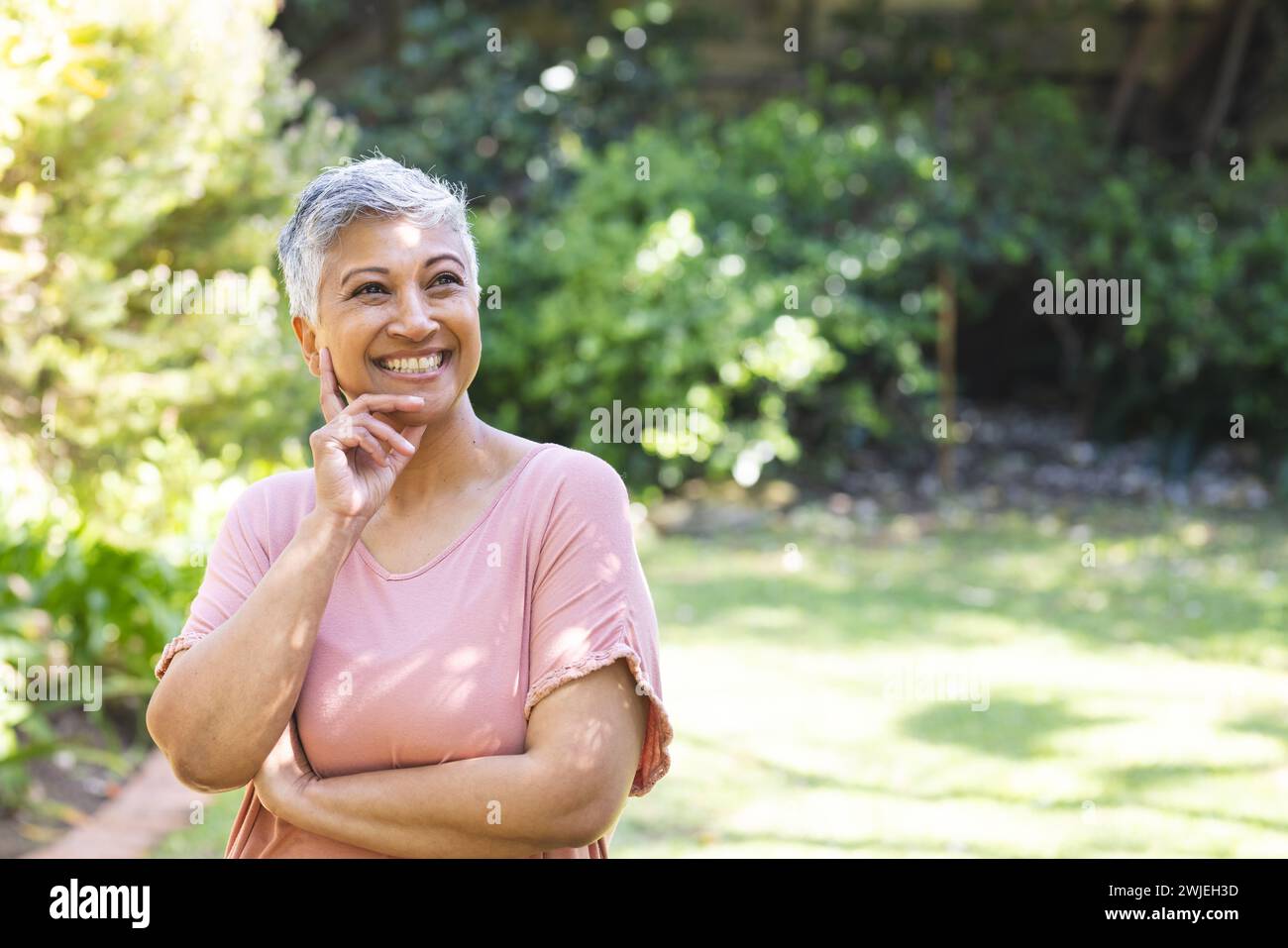 A mature biracial senior woman enjoys a sunny day in the garden, with copy space unaltered Stock Photo