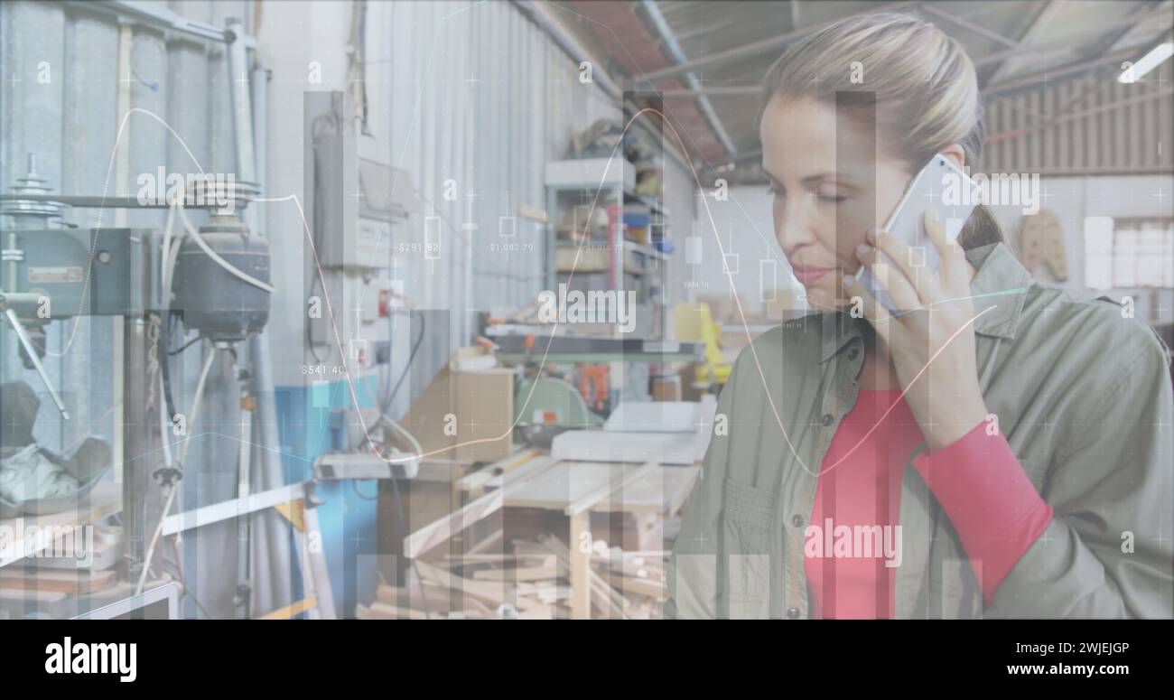 Female architect on phone in a warehouse with graphs Stock Photo