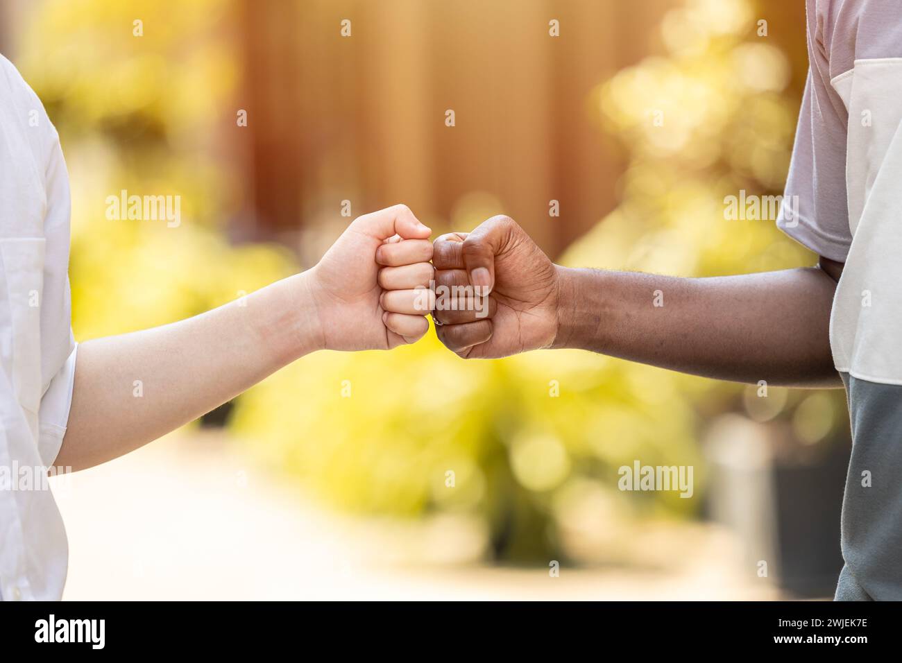 black and white people hand fist bump together to greet friends in modern teenagers. Stock Photo