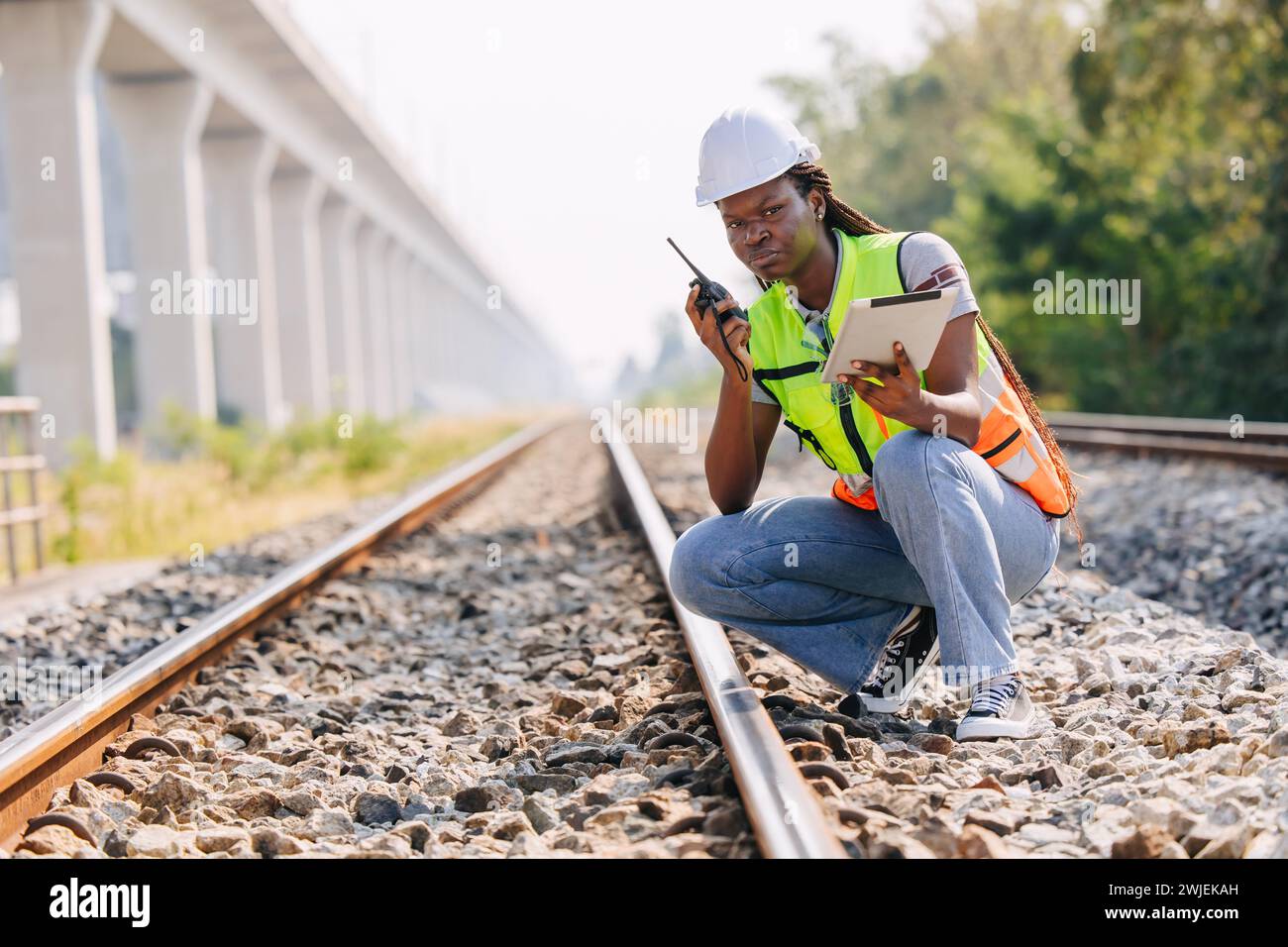 African black engineer women worker work checking service in train railway tracks construction site in transportation industry radio operate Stock Photo