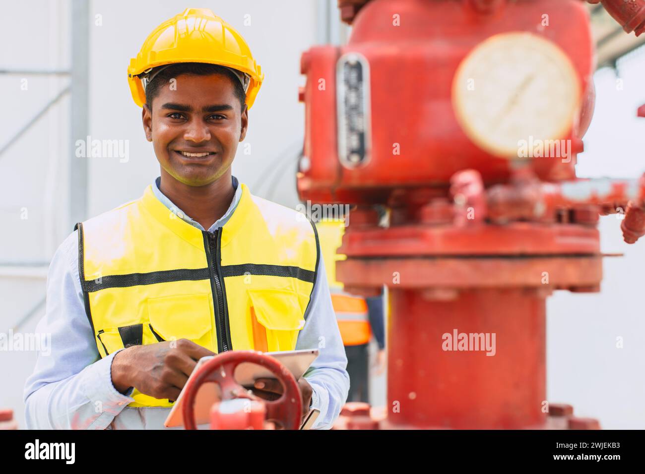 portrait happy indian engineer safety staff worker work control operate valve gas pipe oil industry Stock Photo