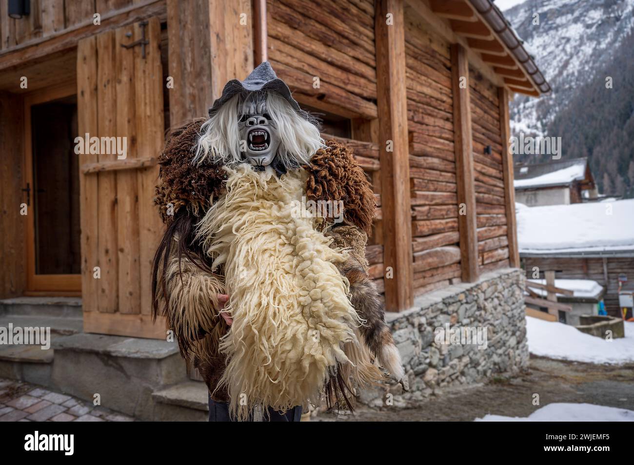 Reveller wearing wooden mask and carnival costume. Evolene, Valais Canton, Switzerland. Stock Photo