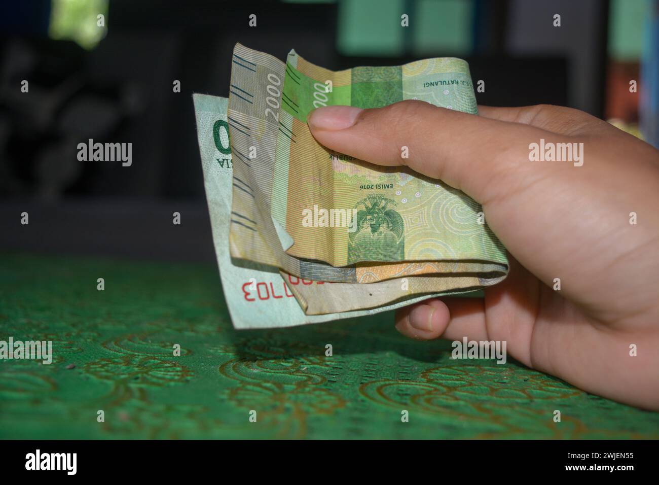 A hand holding a rupiah currency sheet Stock Photo - Alamy