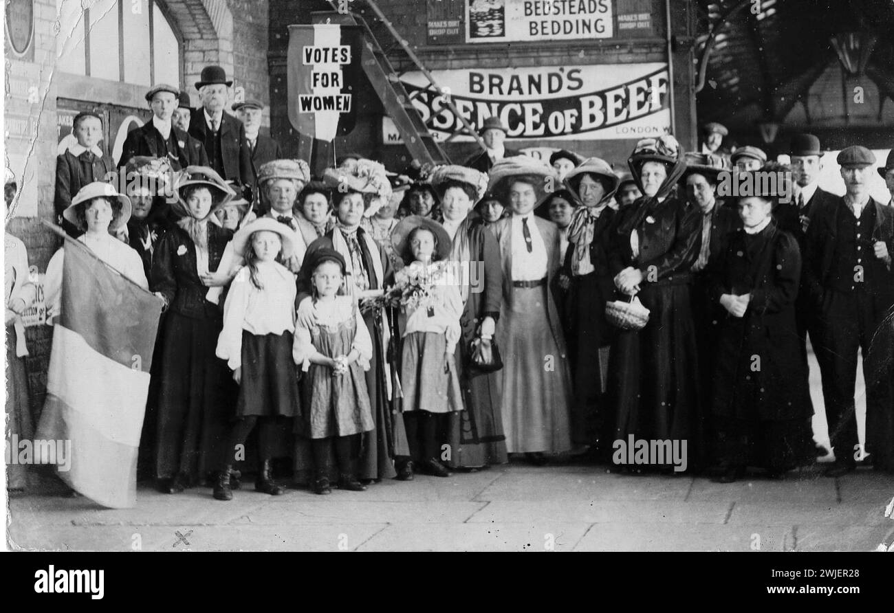 Suffragettes in Redcar, England. 1909.  group portrait of Emmeline Pankhurst and a group of suffragettes, woman on left holding Women's Social & Political Union flag, Votes for Women banner held above group, manuscript inscription reverse: 'Dearest May & Lily I had this card done when I was in Redcar it was taken on the platform at the station Stock Photo