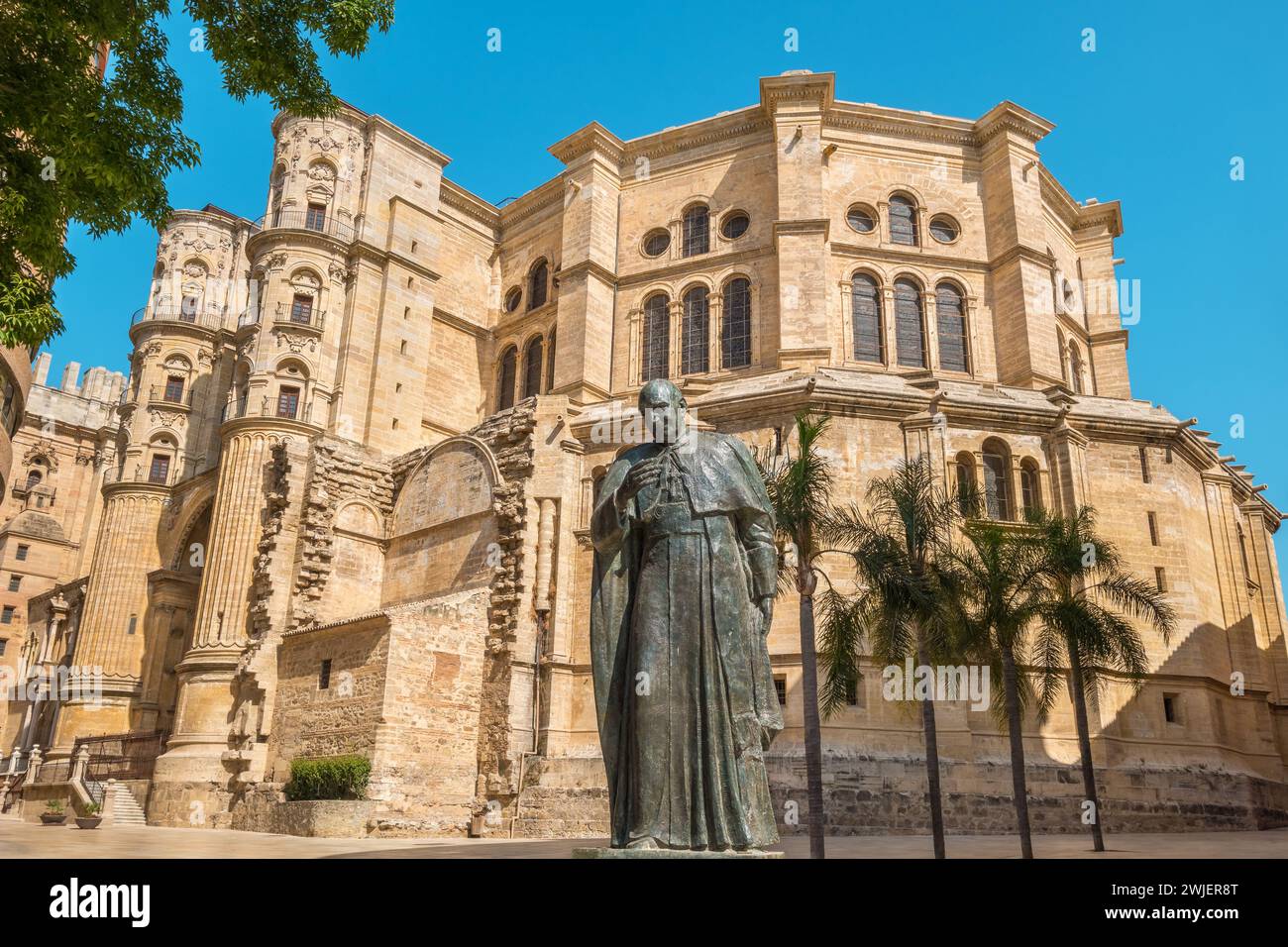 View to facade of Malaga Cathedral (Santa Iglesia Catedral Basílica de la Encarnación) with bishop statue. Malaga, Spain Stock Photo