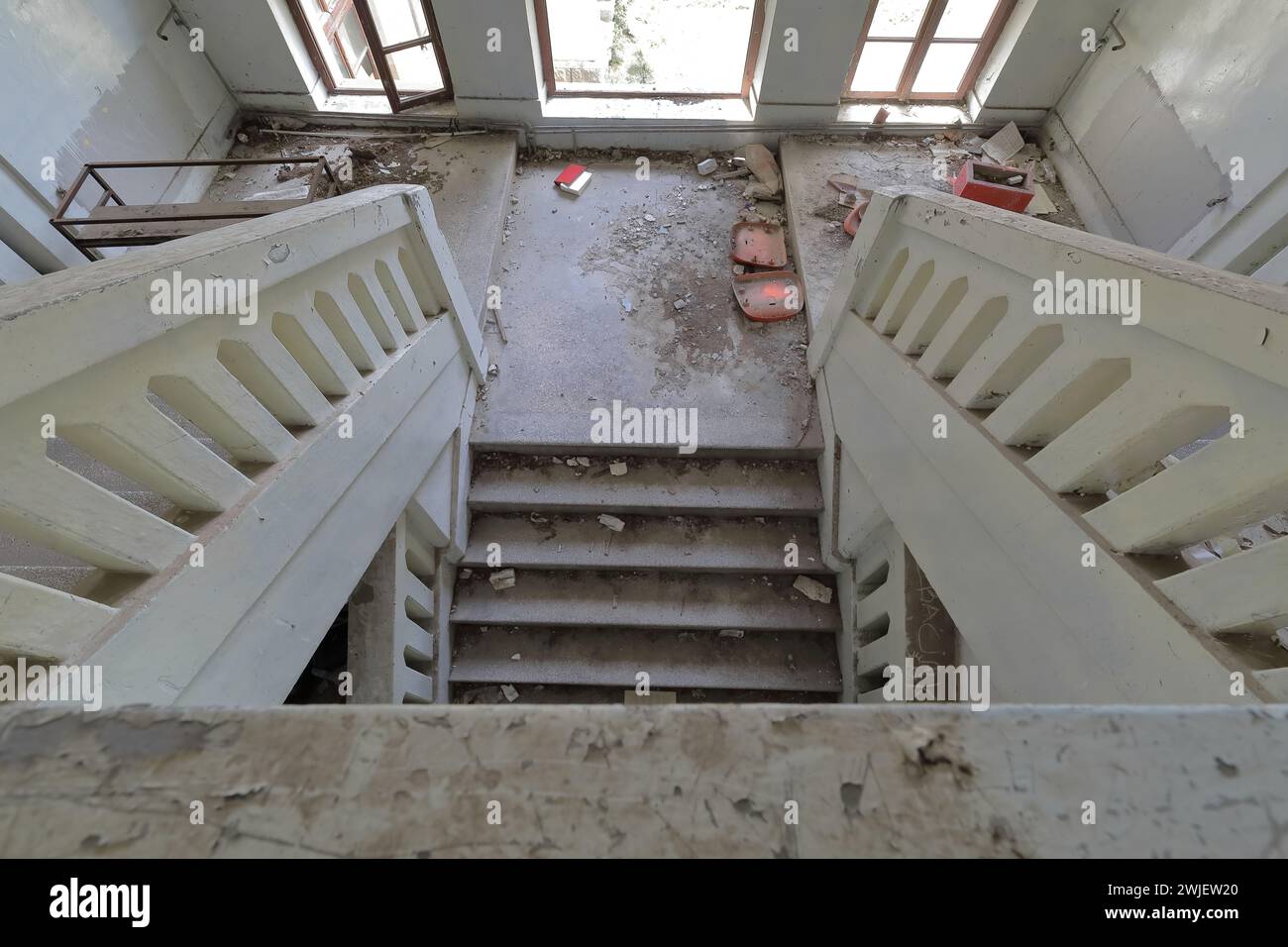 355 Inner stairway of an abandoned former primary school full of rubble, glass lacking window, red book on the floor. Vevchani-North Macedonia. Stock Photo