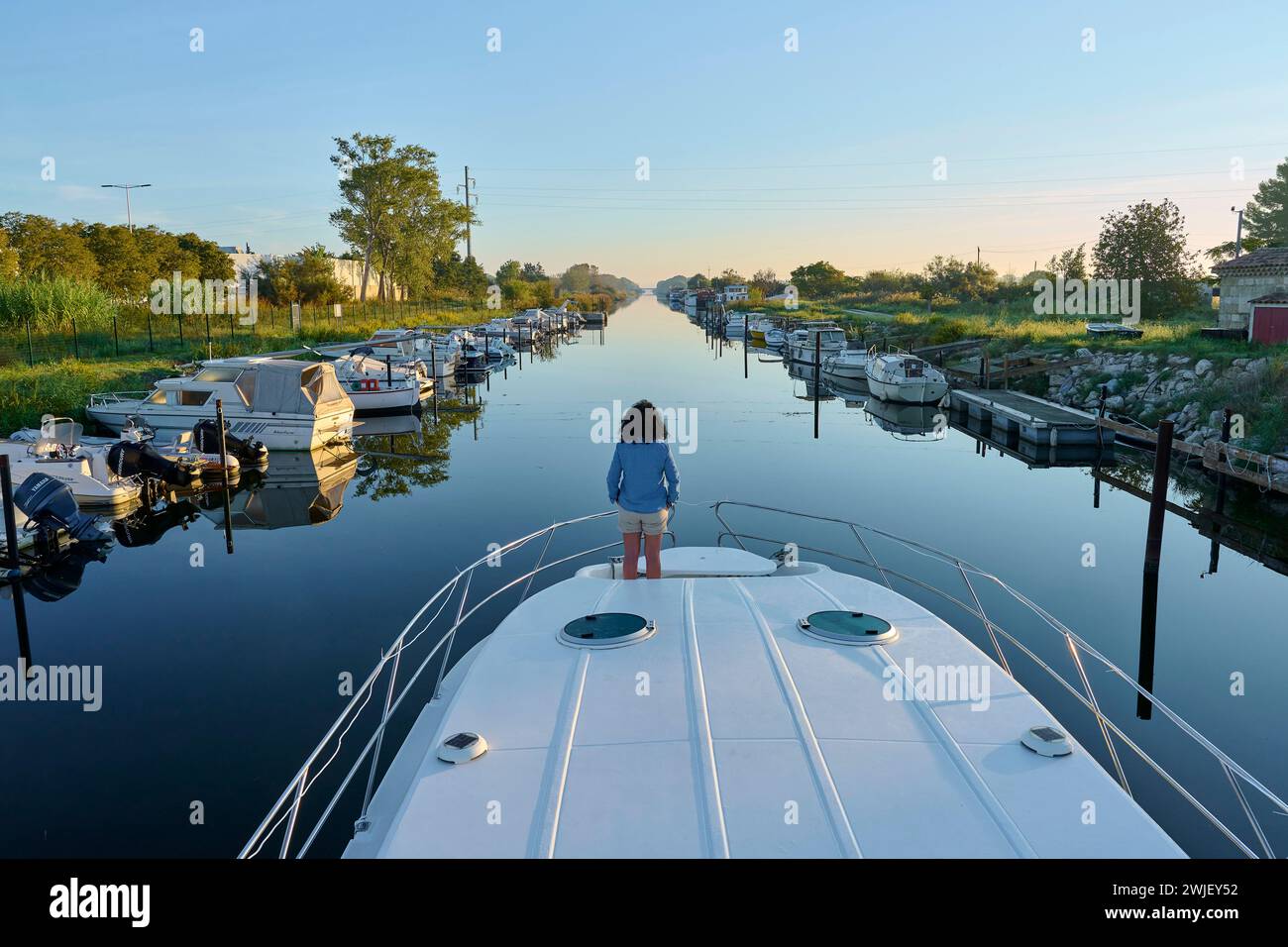 Aigues-Mortes (south of France): tourism on the “canal du Rhone a Sete” (Rhone-Sete Canal). Woman viewed from behind at the bow of a barge on the cana Stock Photo