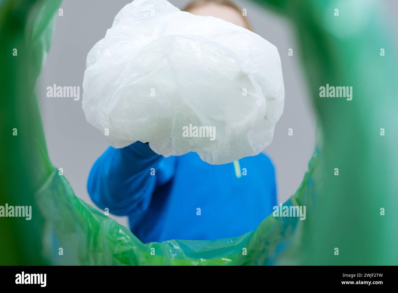 Low angle view child roll up plastic wrap in a trash bin, recycling and waste sorting concept Stock Photo
