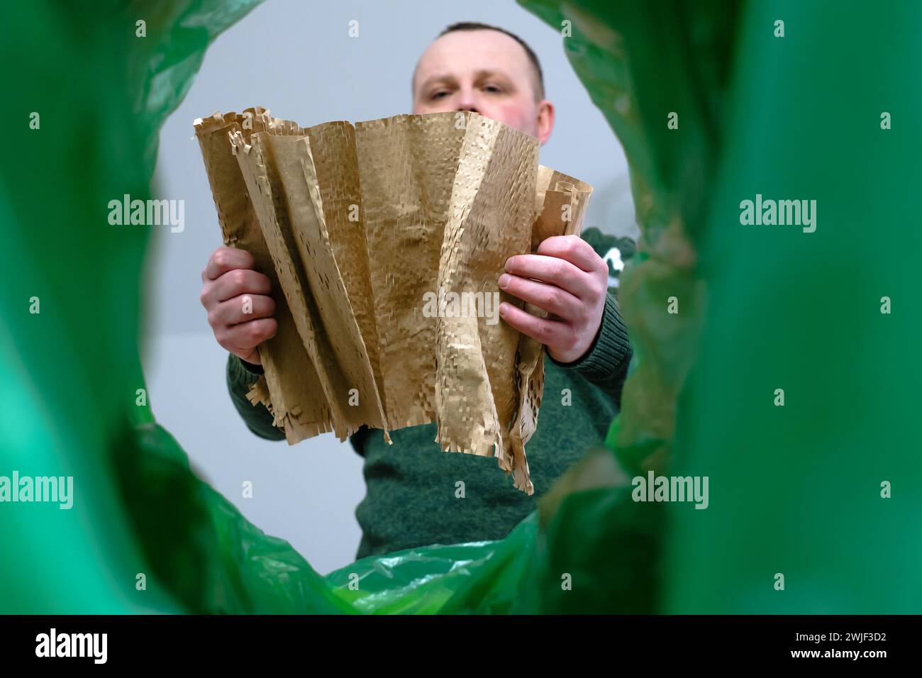 Low angle view male roll up kraft paper or gift packaging wrap in a trash bin, recycling and waste sorting concept. Stock Photo