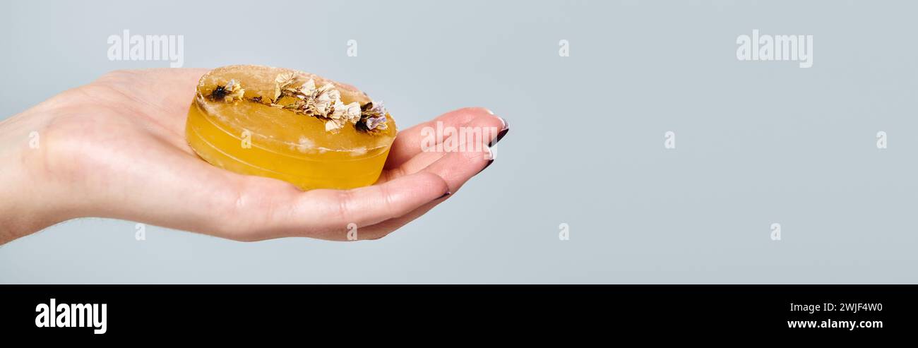 object photo of natural orange soap with decorations in hand of unknown young woman, banner Stock Photo