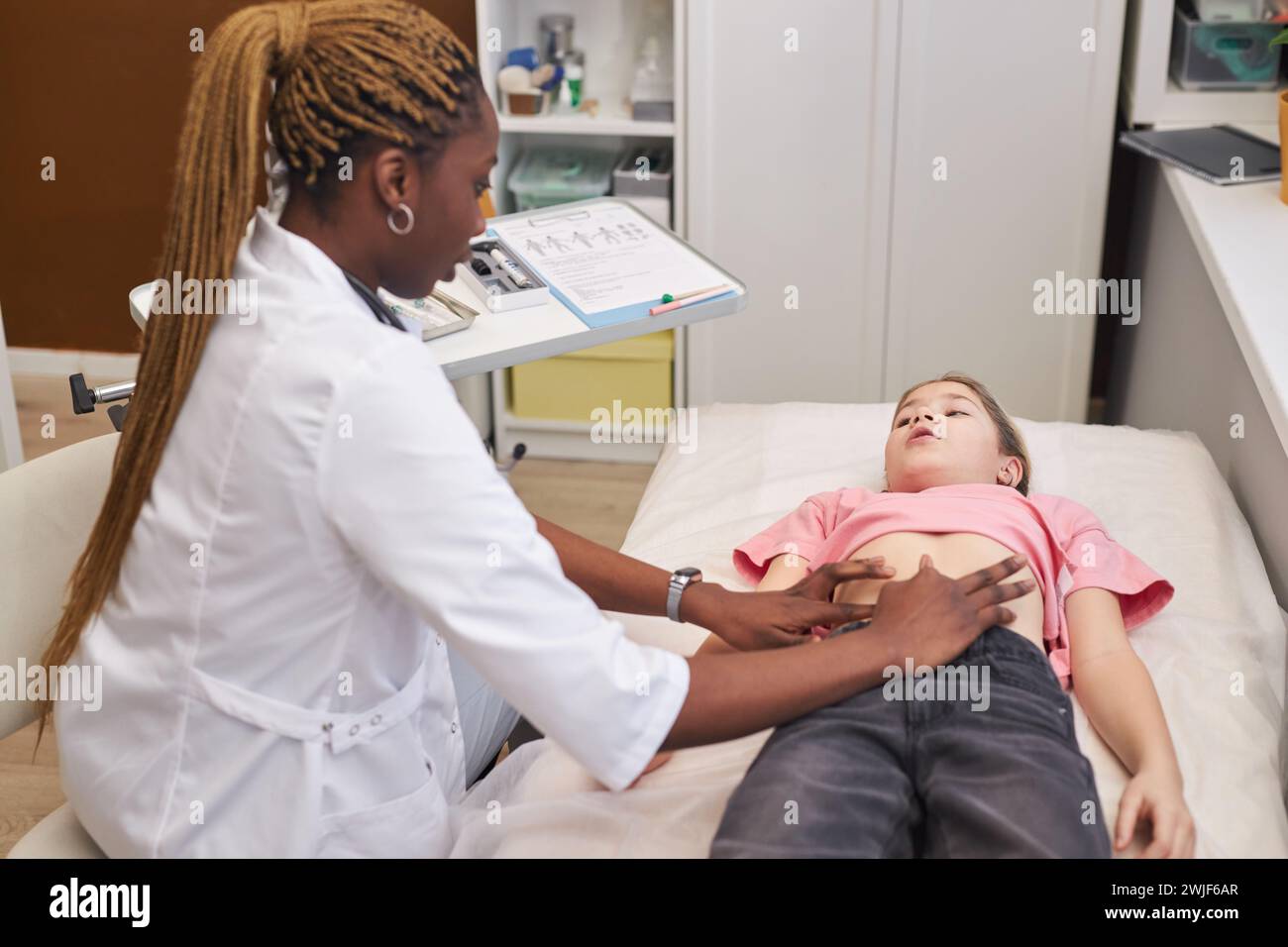 Side view portrait of female doctor palpating stomach of young girl