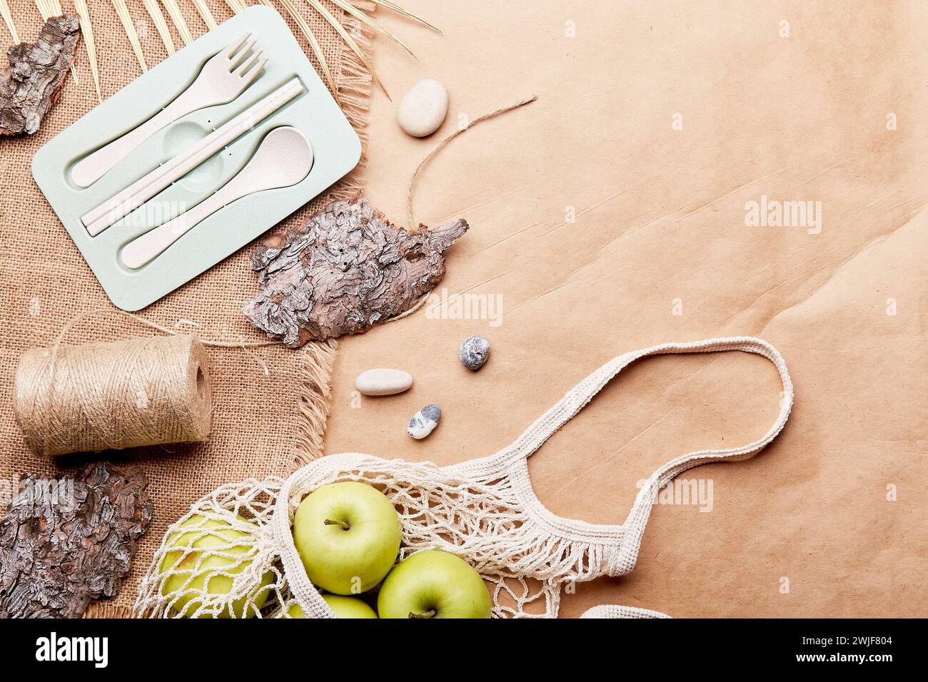 Aesthetic eco-friendly, zero waste, sustainable lifestyle background with reusable bag, cutlery, apples, tree bark, pebbles on crafting paper with cop Stock Photo